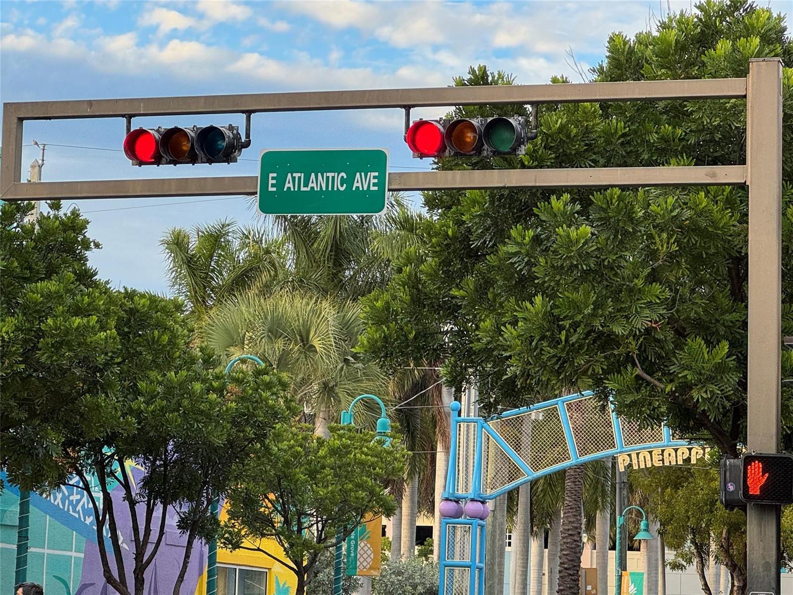 A street sign for E Atlantic Ave hangs beneath traffic lights near a pineapple-themed archway — 1010 NE 8th Avenue # 31f, Delray Beach FL 33483, DELRAY BEACH, FL