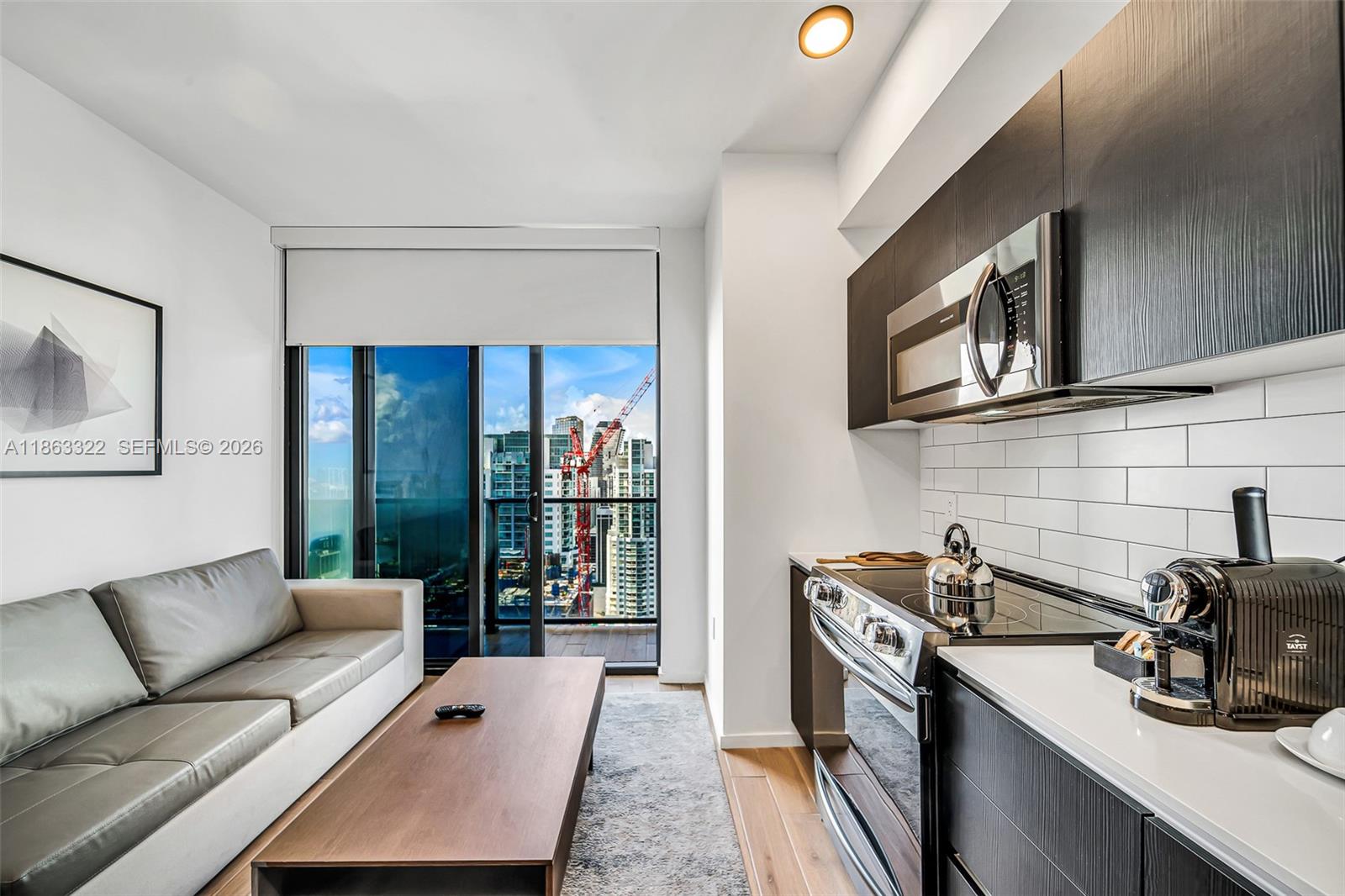 A modern studio apartment features a kitchenette, a sofa, and a balcony with city views — 398 NE 5 # 4416, Miami FL 33132, MIAMI, FL