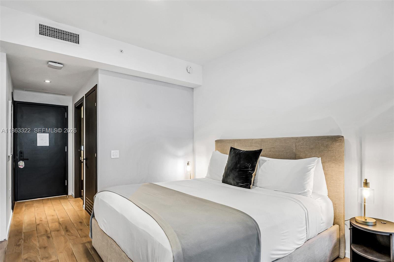 A bedroom features a queen bed with a tan headboard, wood flooring, and a black door — 398 NE 5 # 4416, Miami FL 33132, MIAMI, FL