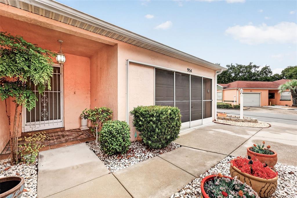 The exterior of a peach-colored house features a screened-in garage and a front entryway — 954 AVALON AVENUE, LADY LAKE, FL