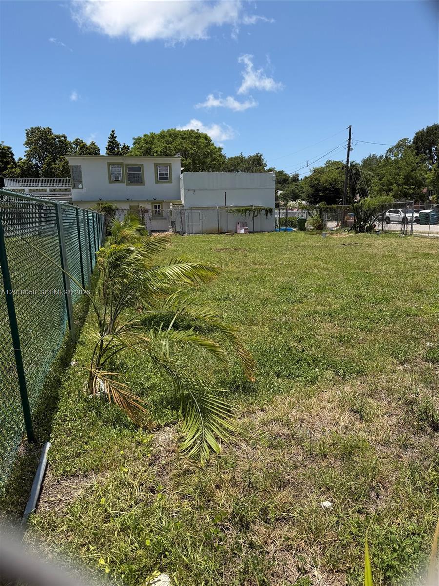 A grassy vacant lot is enclosed by a chain-link fence next to a building — 810 NW 79th St, Miami FL 33150, MIAMI, FL