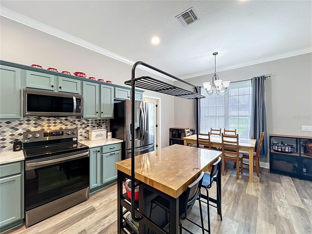 A kitchen features light blue cabinets, a butcher block island, and an adjacent dining area — 300 E GENEVA STREET, OCOEE, FL