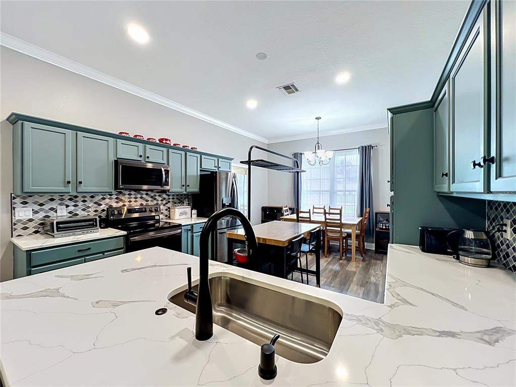 A kitchen with teal cabinets, white marble countertops, and a central island with a sink — 300 E GENEVA STREET, OCOEE, FL