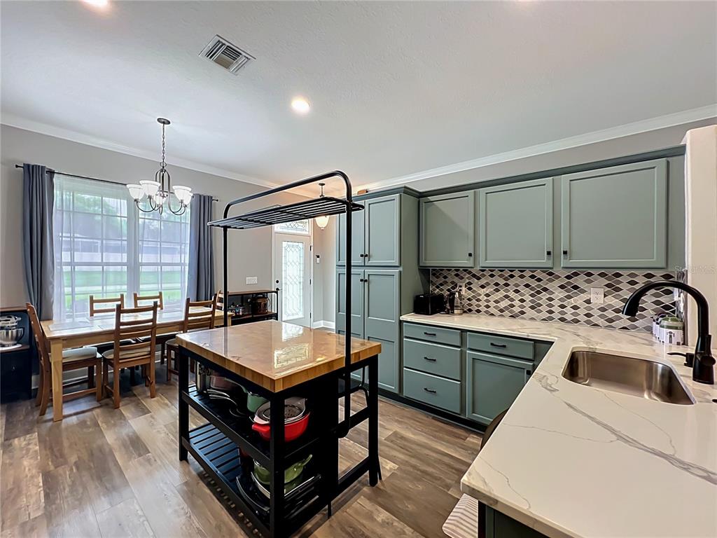 A kitchen features sage green cabinets, a butcher block island, and a marble-look countertop — 300 E GENEVA STREET, OCOEE, FL