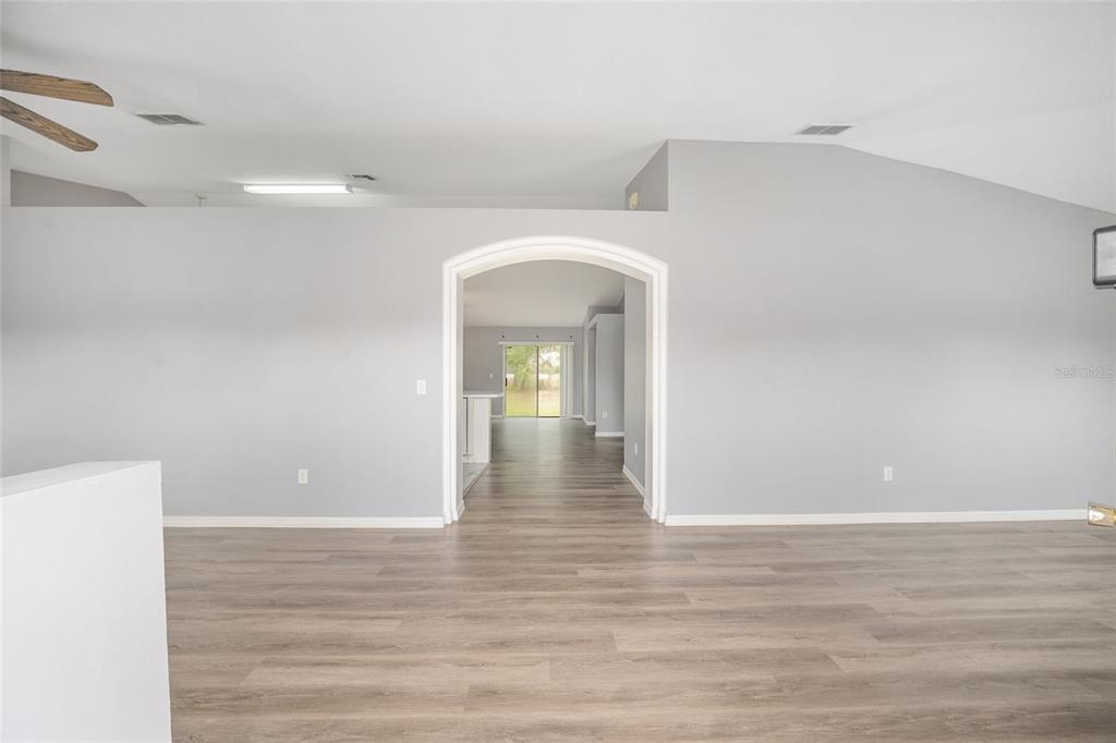 An interior view shows a gray-walled room with wood-look flooring and an arched doorway — 20 PINE COURT LOOP, OCALA, FL