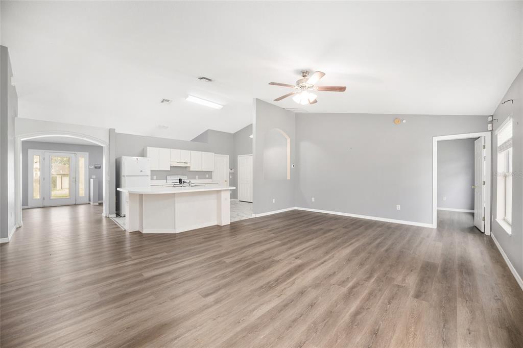 An open-concept living area with gray walls, wood-look flooring, and a white kitchen island — 20 PINE COURT LOOP, OCALA, FL