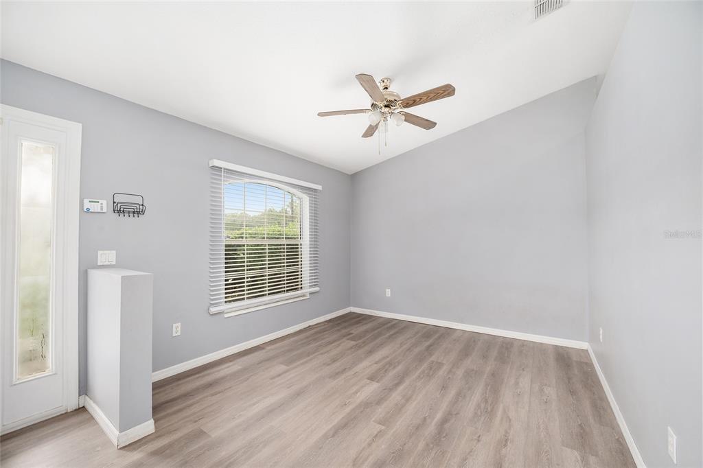 An empty room with light gray walls, wood-look flooring, a ceiling fan, and a window — 20 PINE COURT LOOP, OCALA, FL