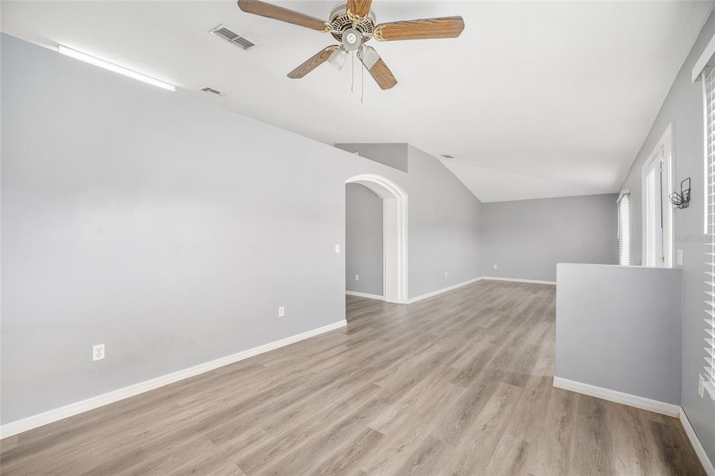 An empty room with light gray walls, wood-look flooring, a ceiling fan, and an arched doorway — 20 PINE COURT LOOP, OCALA, FL