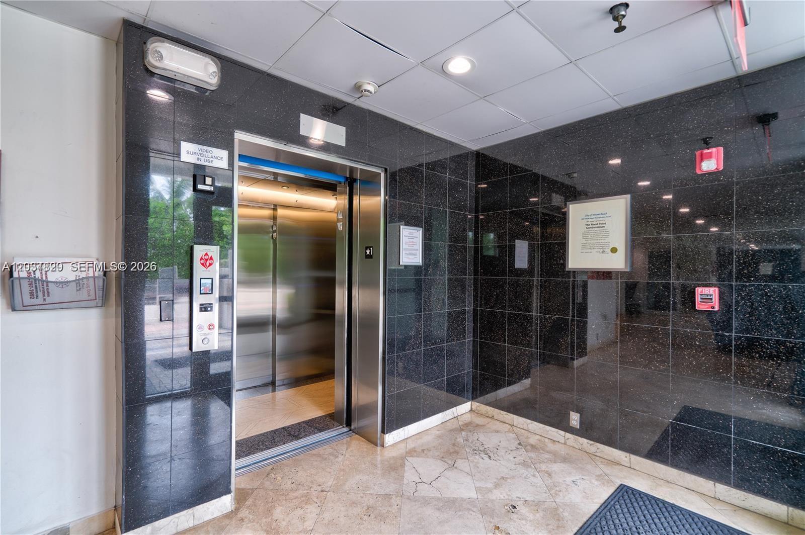 An elevator with stainless steel doors is set into a black tiled wall — 7800 Collins Ave # 508, Miami Beach FL 33141, MIAMI BEACH, FL