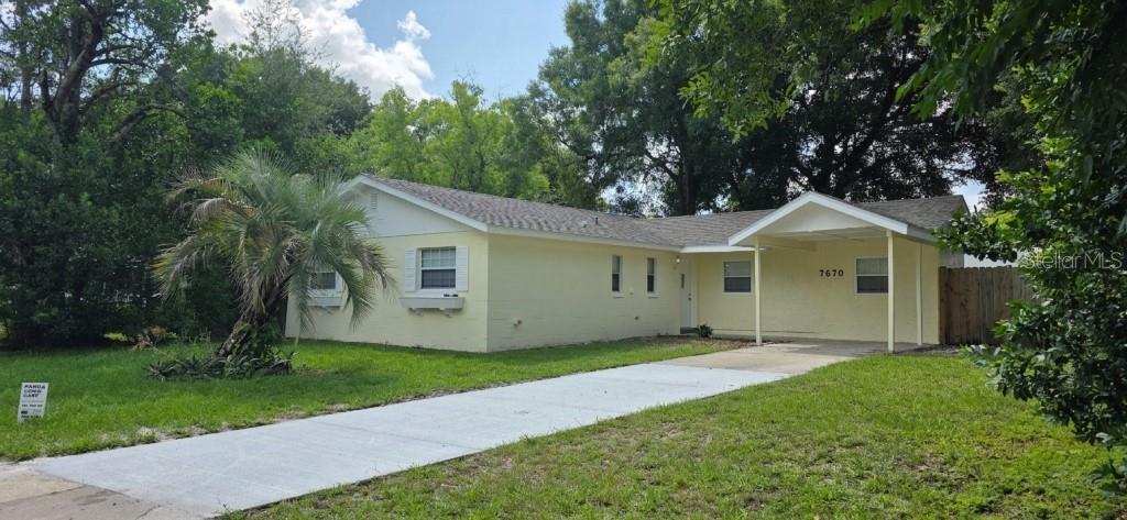 A single-story yellow house with a carport and a concrete driveway sits on a lawn — 7670 STRATFORD BOULEVARD, ORLANDO, FL