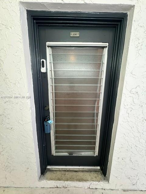 A dark-framed exterior door with a frosted glass panel and the number 106 above it — LAUDERHILL, FL