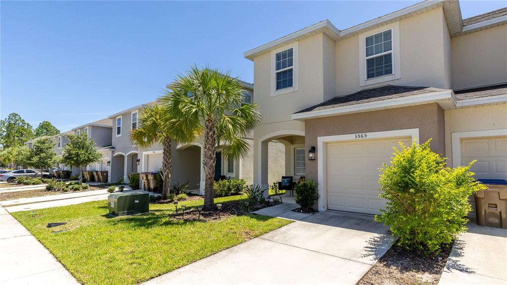 A two-story townhouse with a beige stucco exterior, a single-car garage, and a front lawn — 3565 ANIBAL STREET, KISSIMMEE, FL