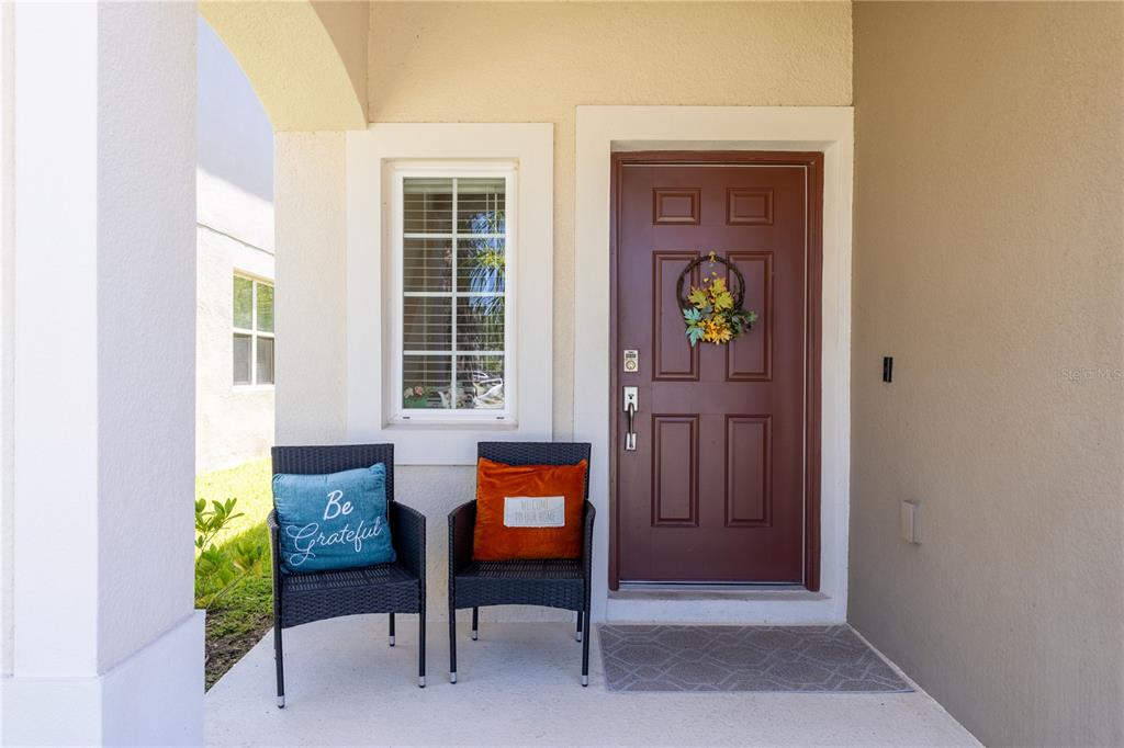 A covered front porch features two wicker chairs, a window, and a brown front door — 3565 ANIBAL STREET, KISSIMMEE, FL