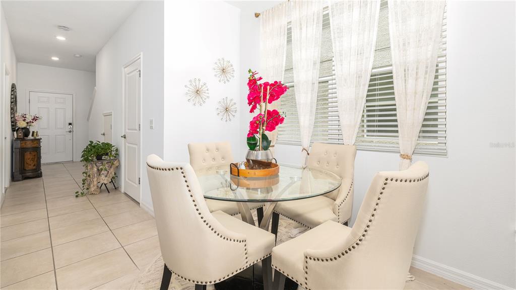 A dining area features a glass-topped table, four upholstered chairs, and wall-mounted starburst decorations — 3565 ANIBAL STREET, KISSIMMEE, FL