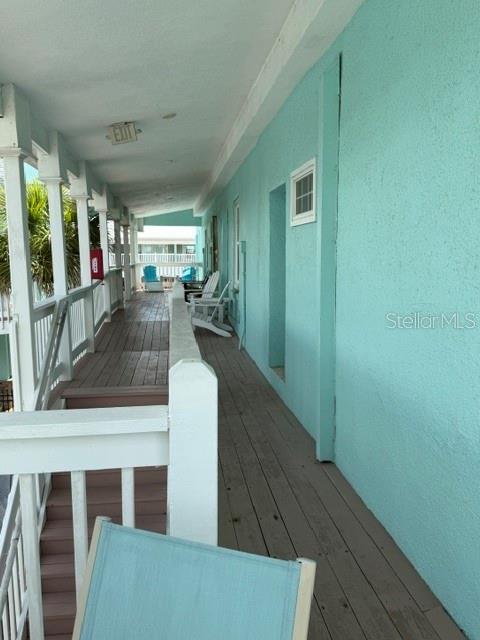 A wooden balcony walkway runs alongside a turquoise exterior wall with white railings and chairs — 301 S CENTRAL AVENUE UNIT 10, FLAGLER BEACH, FL