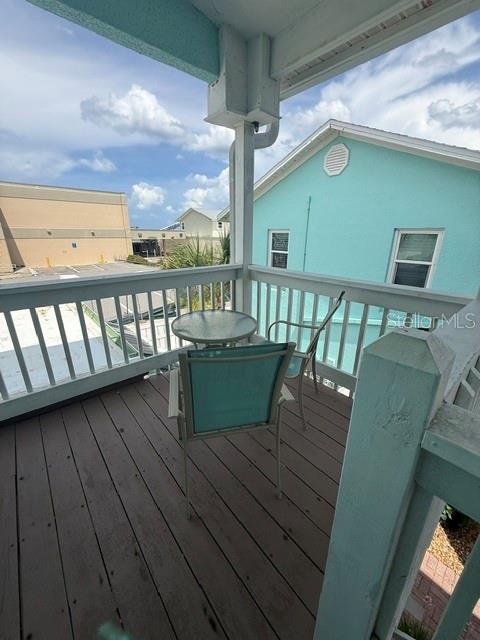 A wooden balcony features a small round table and two chairs overlooking a neighboring building — 301 S CENTRAL AVENUE UNIT 10, FLAGLER BEACH, FL