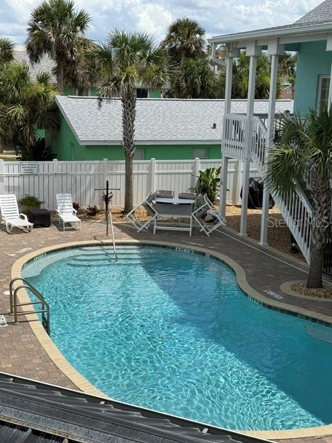A swimming pool sits in a backyard patio area next to a white house — 301 S CENTRAL AVENUE UNIT 10, FLAGLER BEACH, FL