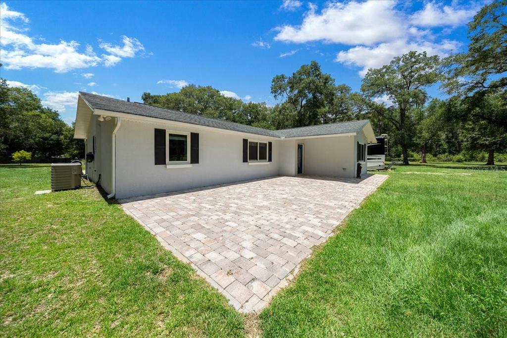 A white house with a paved patio and black shutters sits on a grassy lot — 6150 S HIGHWAY 314A, OCKLAWAHA, FL