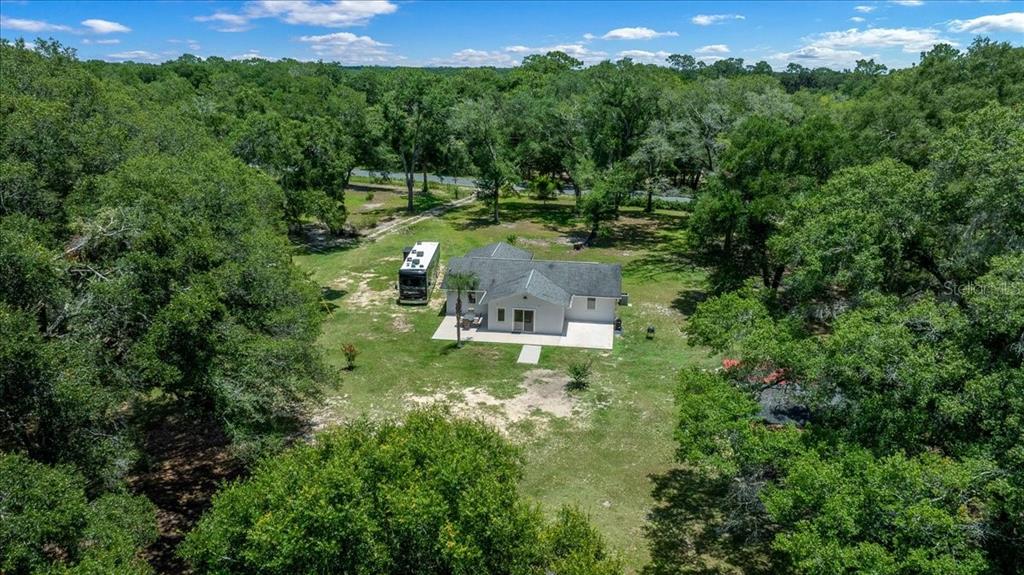 An aerial view shows a single-story house with a parked RV on a wooded lot — 6150 S HIGHWAY 314A, OCKLAWAHA, FL