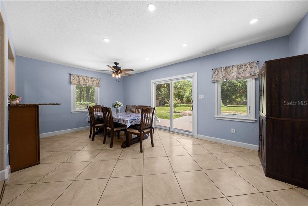 A dining room with blue walls, tile flooring, a wooden table, and sliding glass doors — 6150 S HIGHWAY 314A, OCKLAWAHA, FL