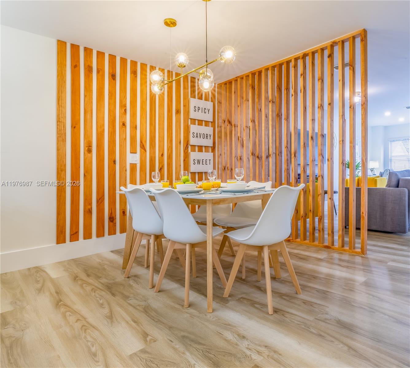 A dining area features a wooden slat wall, a modern light fixture, and white chairs — 1762 NW 15th St, Miami FL 33125, MIAMI, FL
