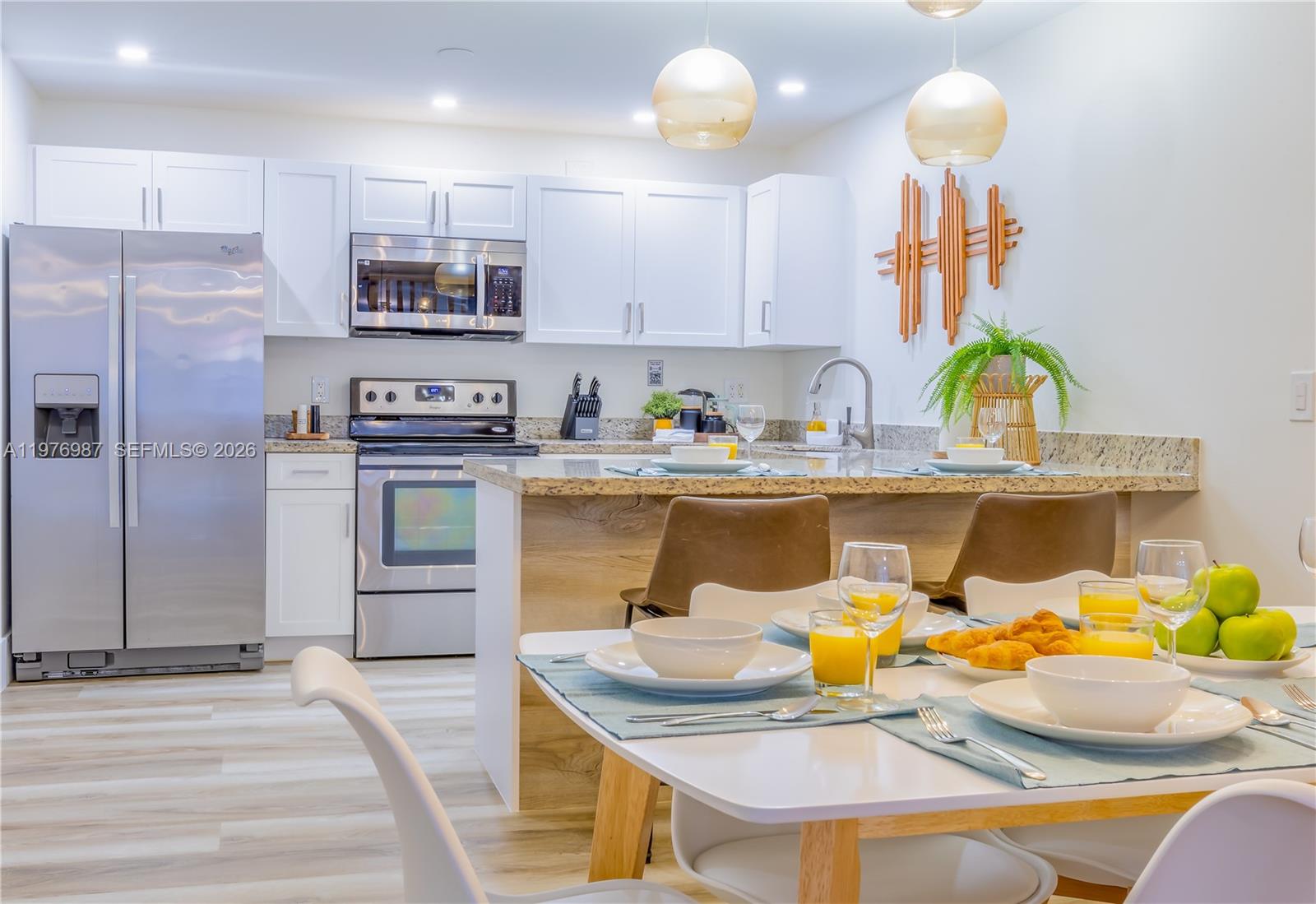A modern kitchen features white cabinets, stainless steel appliances, and a dining table with place settings — 1762 NW 15th St, Miami FL 33125, MIAMI, FL