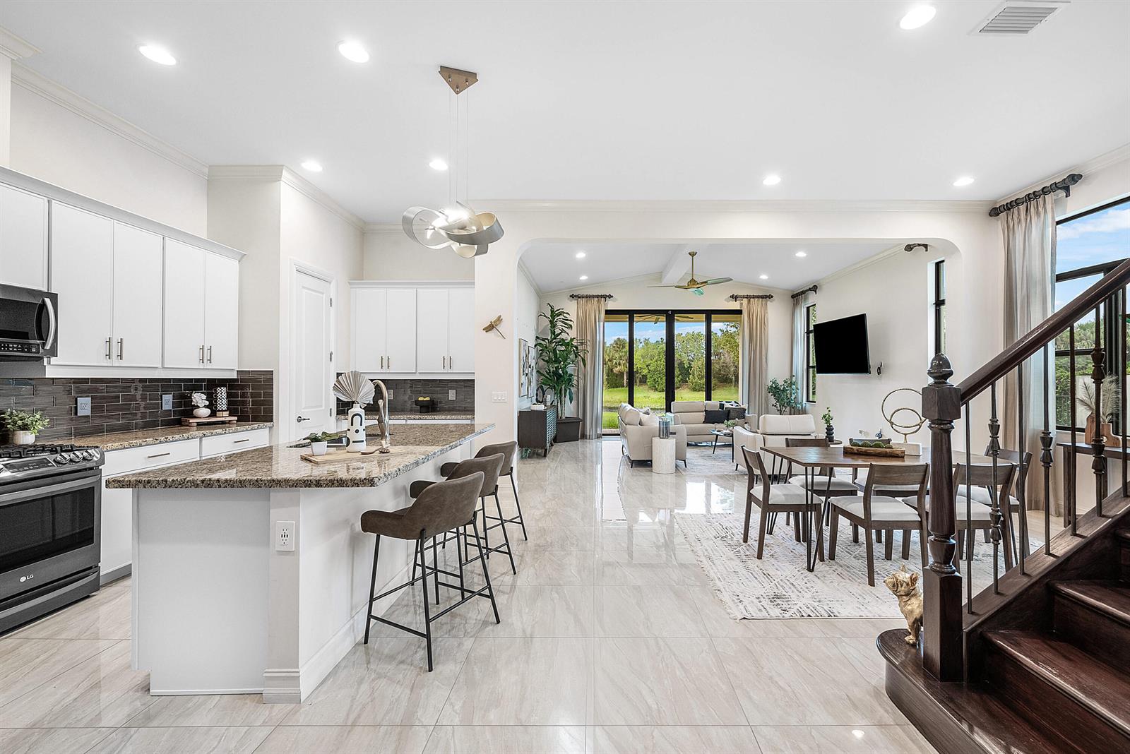An open-concept kitchen, dining area, and living room featuring white cabinetry and tile flooring — 9091 Grand Prix Lane, Boynton Beach FL 33472, BOYNTON BEACH, FL