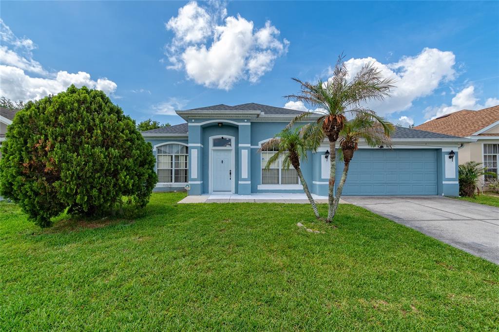 A blue single-story house with a two-car garage, a palm tree, and a large bush — 2818 OCONNELL DRIVE, KISSIMMEE, FL