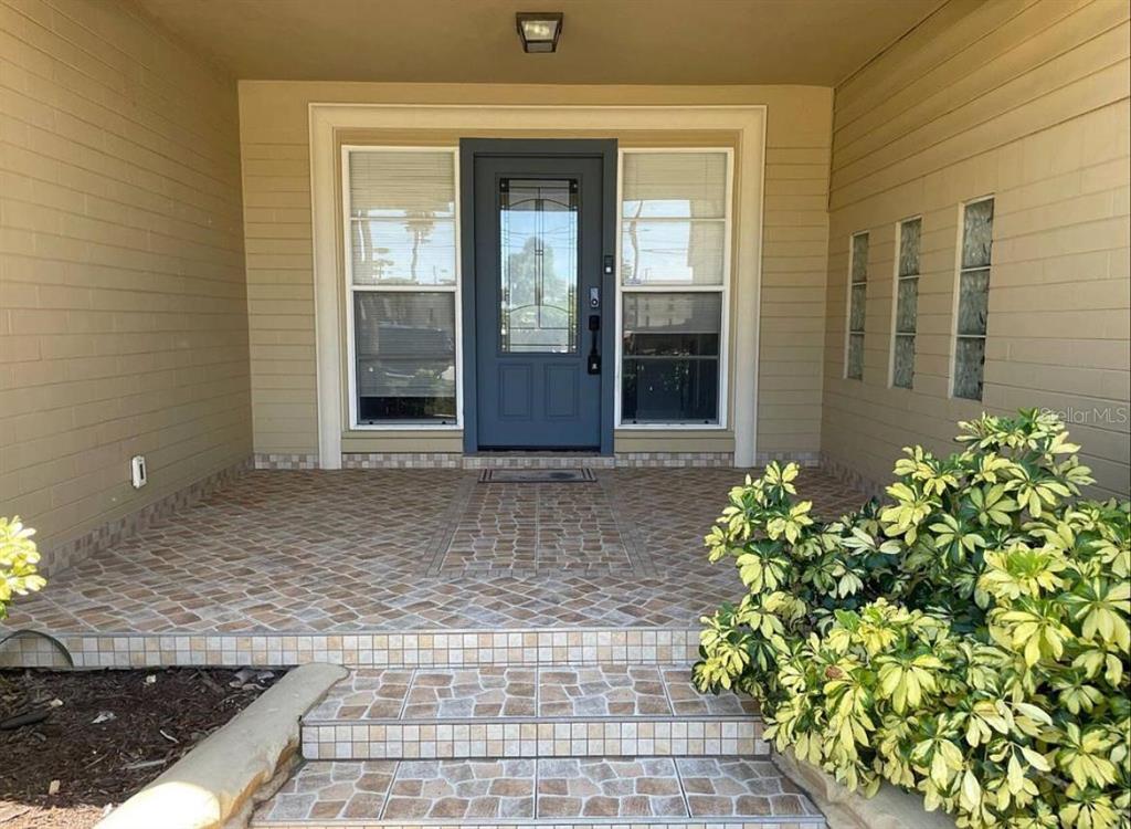 A front entryway features a blue door, tiled porch, steps, and a large potted plant — 582 REVILO BOULEVARD, DAYTONA BEACH, FL