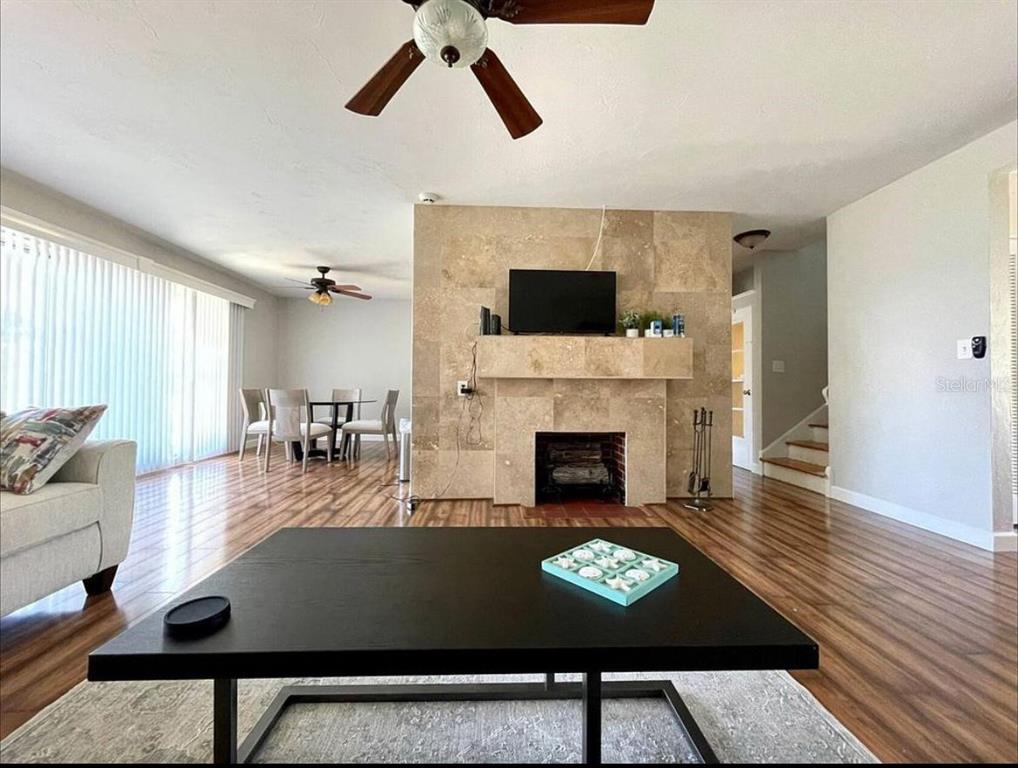 A living room with wood floors, a stone fireplace, and a dining area in the background — 582 REVILO BOULEVARD, DAYTONA BEACH, FL