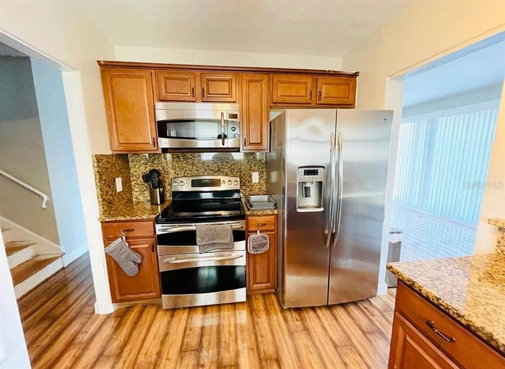 A kitchen features wood cabinets, granite countertops, and stainless steel appliances — 582 REVILO BOULEVARD, DAYTONA BEACH, FL