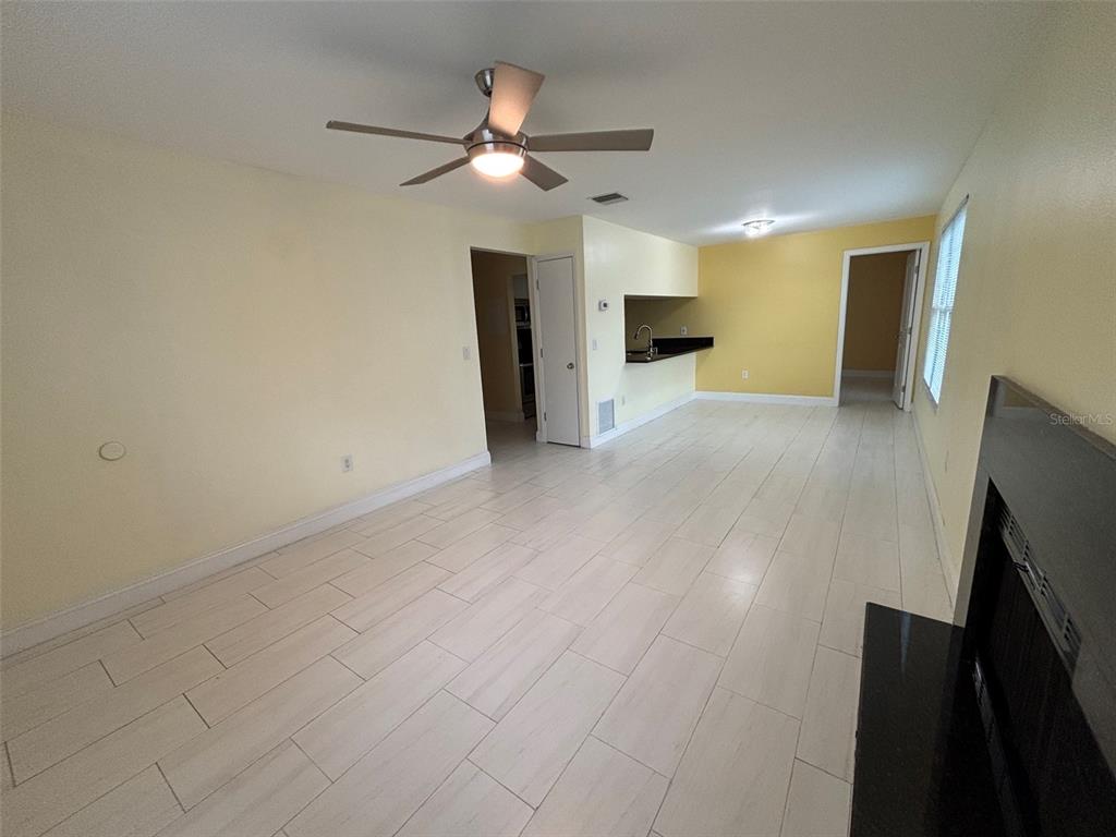 A living room with light-colored tile flooring, a ceiling fan, and a fireplace — 3638 59TH AVENUE W UNIT 3638, BRADENTON, FL