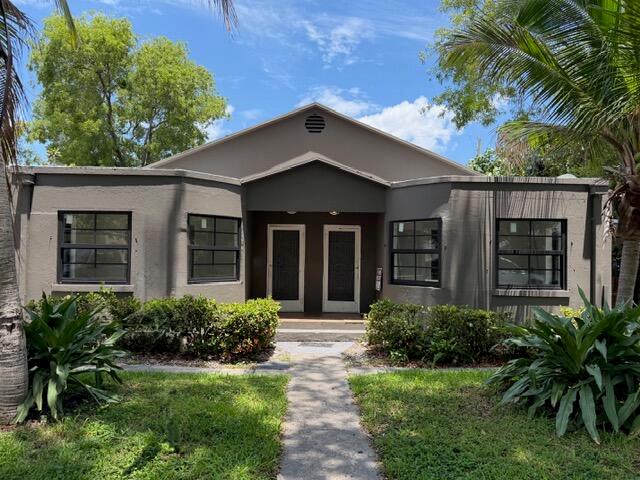 A single-story duplex with a gray exterior, two front doors, and surrounding landscaping — 521 48th Street, West Palm Beach FL 33407, WEST PALM BEACH, FL