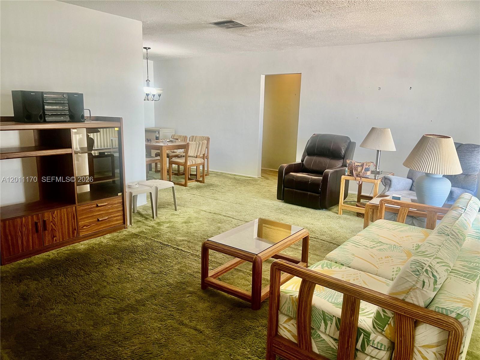 A living room features green wall-to-wall carpeting, wood furniture, and a patterned sofa — 4402 NW 43rd Ter, Tamarac FL 33319, TAMARAC, FL