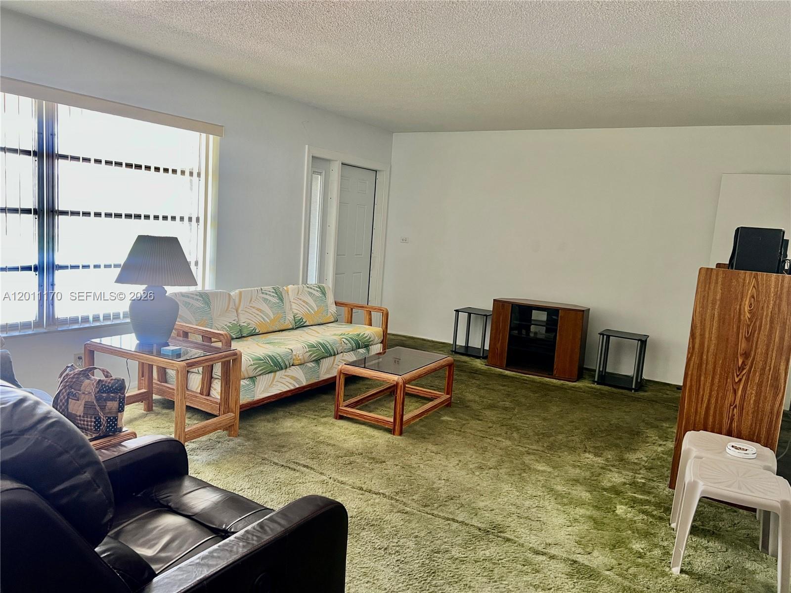 A living room features green wall-to-wall carpeting, a patterned sofa, and a glass-topped coffee table — 4402 NW 43rd Ter, Tamarac FL 33319, TAMARAC, FL