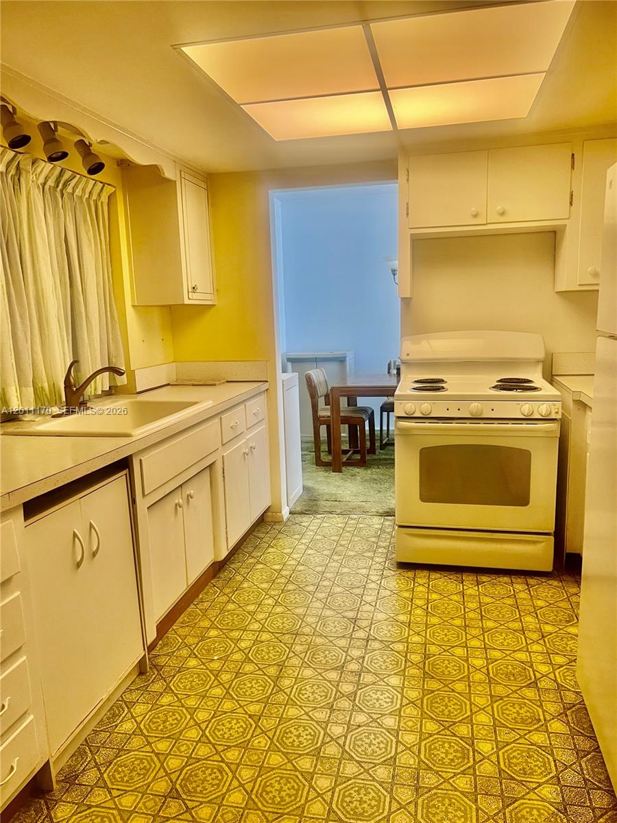 A kitchen features white cabinets, a white stove, and yellow patterned vinyl flooring — 4402 NW 43rd Ter, Tamarac FL 33319, TAMARAC, FL
