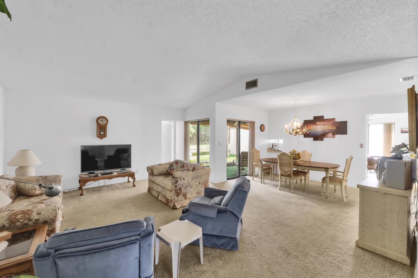 A living and dining room with beige carpet, white walls, and a vaulted ceiling — 4306 Acacia Circle, Coconut Creek FL 33066, COCONUT CREEK, FL