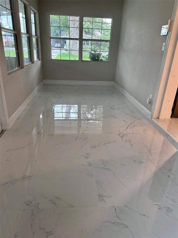 A sunroom features large windows and polished white marble-look tile flooring — 1601 ROSELAWN STREET SW, WINTER HAVEN, FL