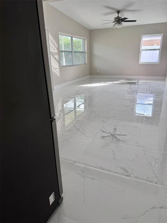 An empty room features white marble-look tile flooring, light-colored walls, and a ceiling fan — 1601 ROSELAWN STREET SW, WINTER HAVEN, FL
