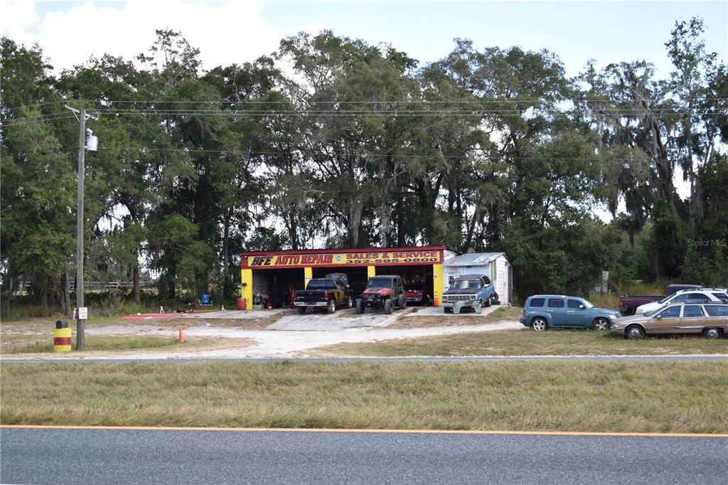 An auto repair shop with three service bays sits in front of a wooded area — 15551 N US HIGHWAY 301, CITRA, FL