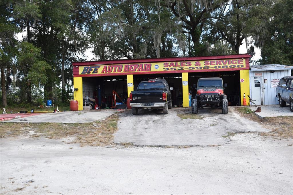 An exterior view of a yellow and red auto repair shop with two service bays — 15551 N US HIGHWAY 301, CITRA, FL