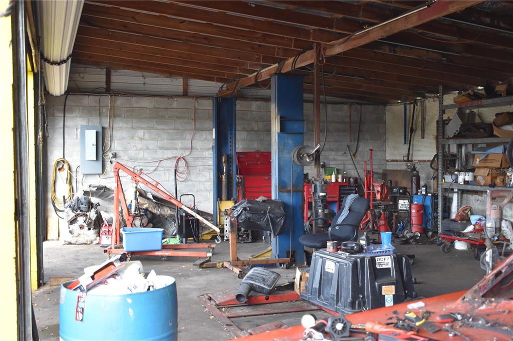 A cluttered automotive repair garage featuring a vehicle lift, tools, and storage shelving — 15551 N US HIGHWAY 301, CITRA, FL