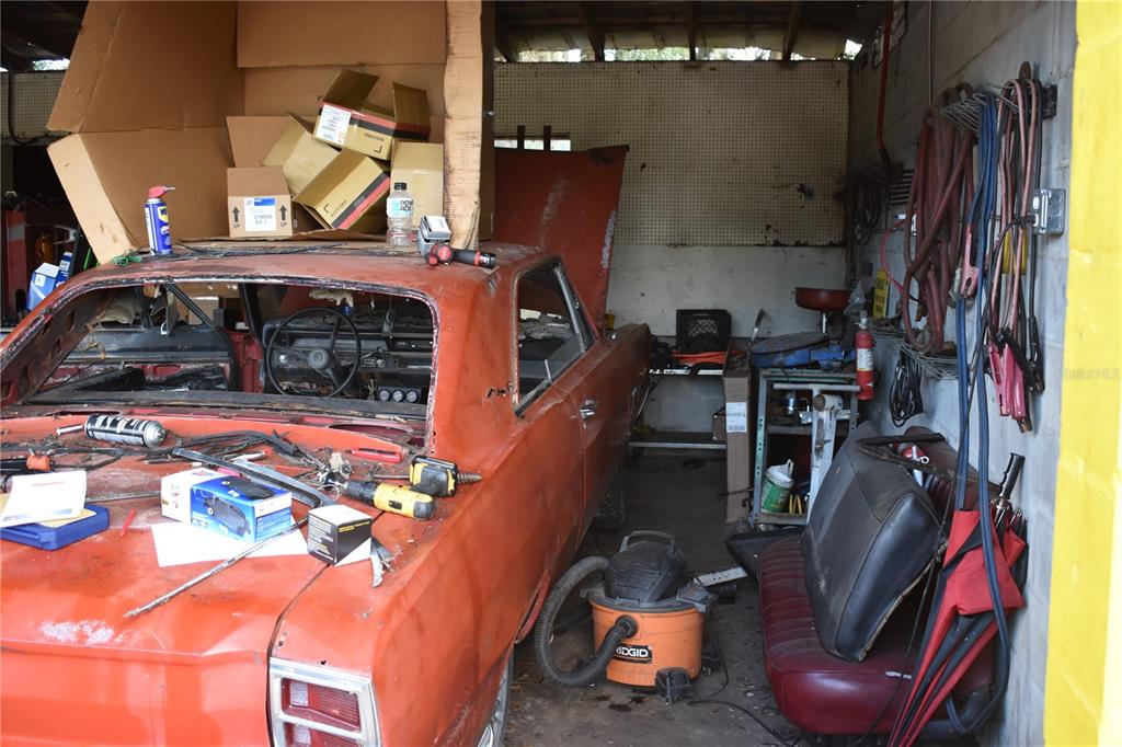 A cluttered garage contains an orange vintage car under repair and various tools and equipment — 15551 N US HIGHWAY 301, CITRA, FL