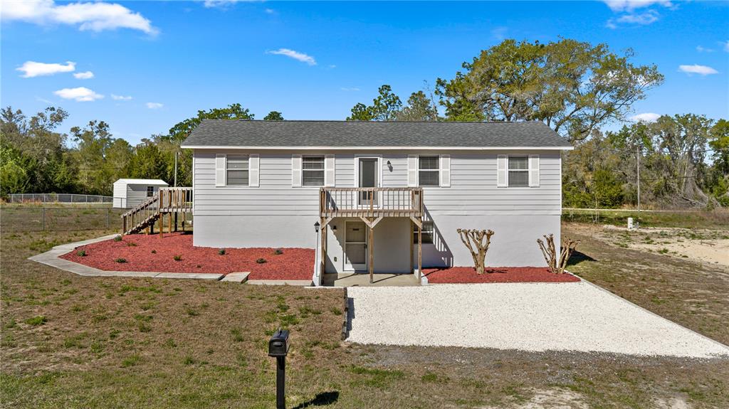 A two-story house with gray siding, a wooden deck, and a gravel driveway — 2800 SW 141ST COURT, OCALA, FL