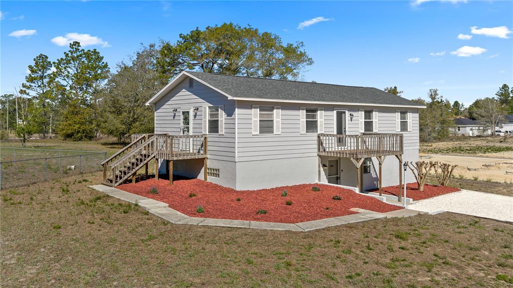 A light gray elevated house with two wooden decks and red mulch landscaping — 2800 SW 141ST COURT, OCALA, FL