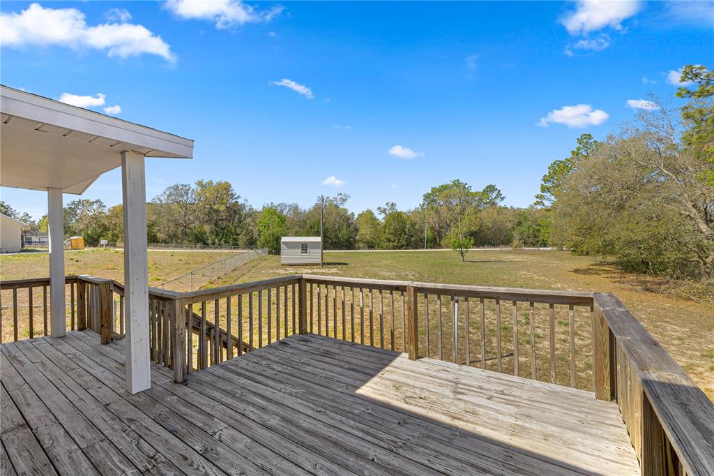 A wooden deck overlooks a large, grassy backyard with a small shed and trees — 2800 SW 141ST COURT, OCALA, FL
