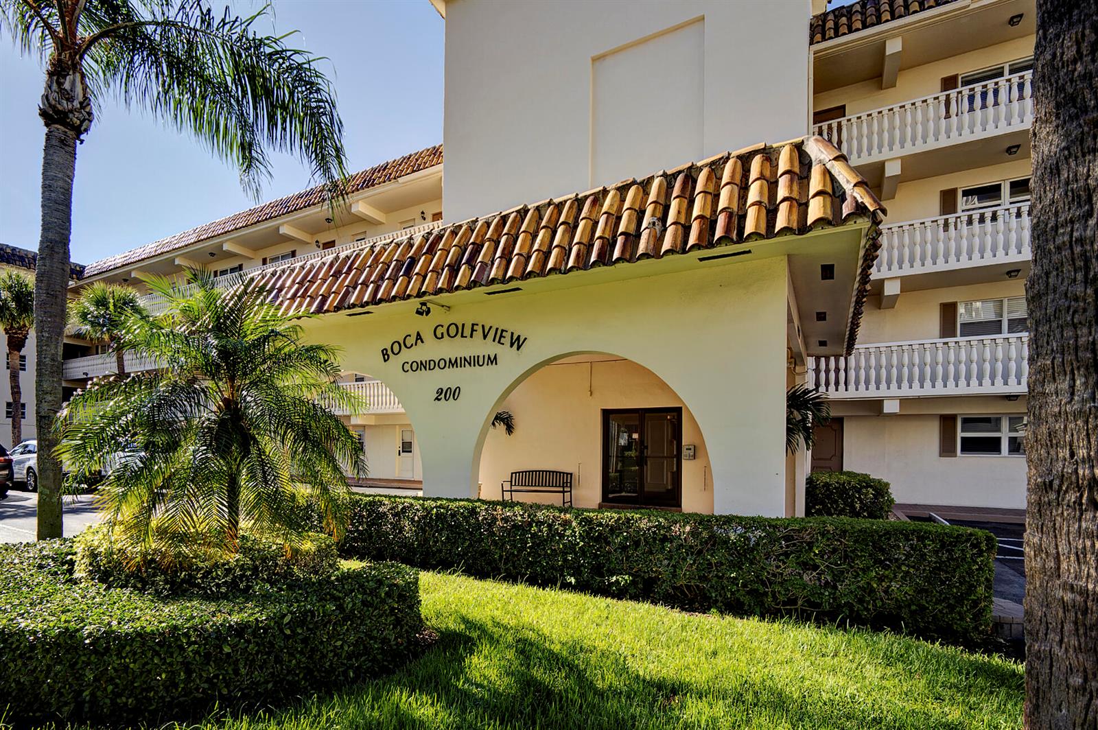 The exterior of a multi-story condominium building features a tiled awning and palm trees — 200 E Royal Palm Road # 2110, Boca Raton FL 33432, BOCA RATON, FL