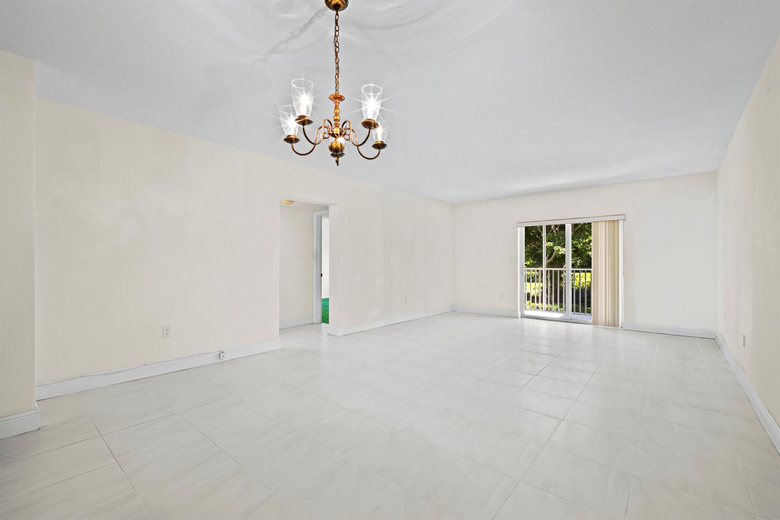An empty room with white tile floors, a chandelier, and a sliding glass door — 200 E Royal Palm Road # 2110, Boca Raton FL 33432, BOCA RATON, FL