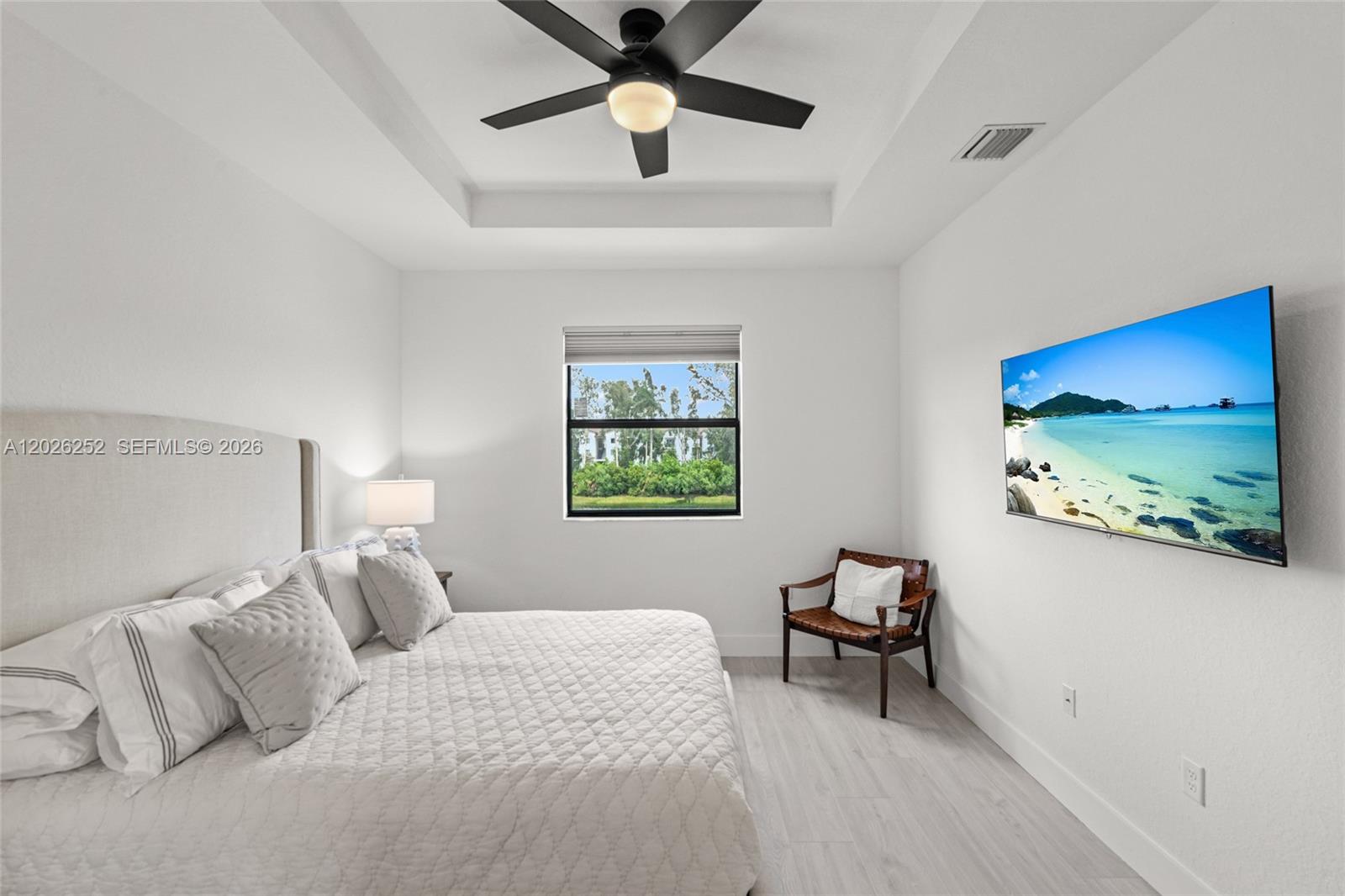 A bedroom features a tray ceiling with a fan, a bed, and a wall-mounted television — 577 NW 204th St, Miami Gardens FL 33169, MIAMI GARDENS, FL