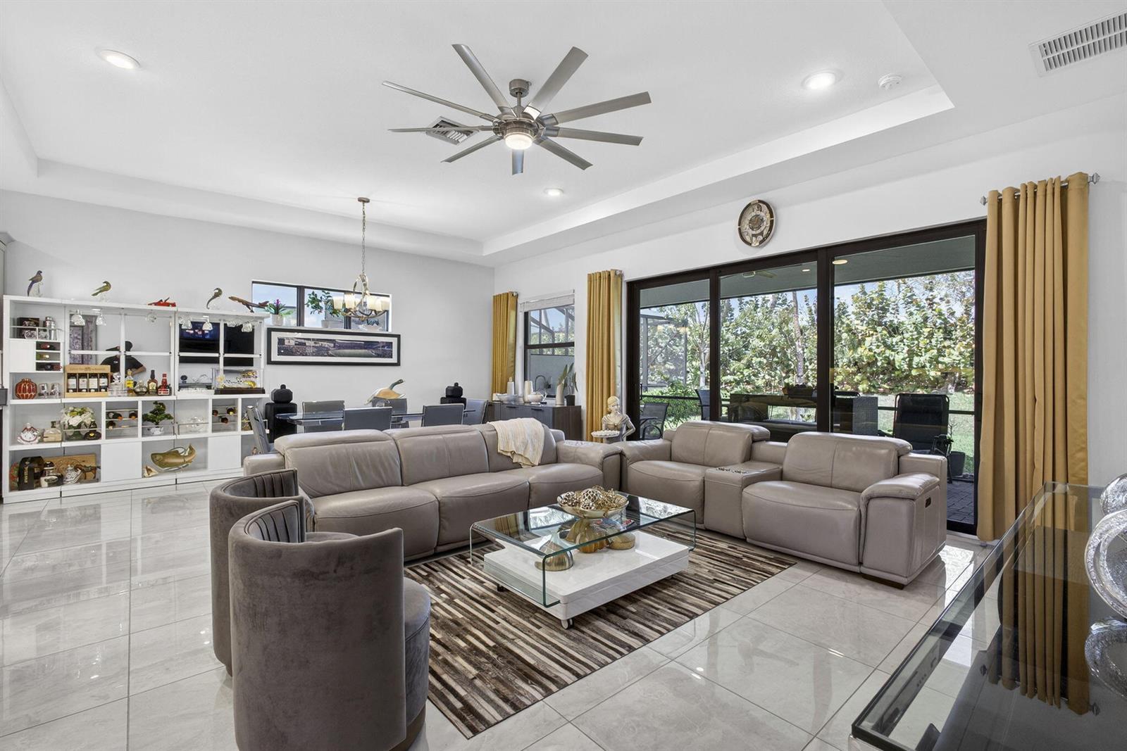 A living room features light gray tile floors, a large sectional sofa, and glass sliding doors — 5492 St Armands Way, Westlake FL 33470, WESTLAKE, FL